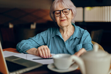 elderly woman working in front of laptop monitor sitting Retired woman chatting unaltered