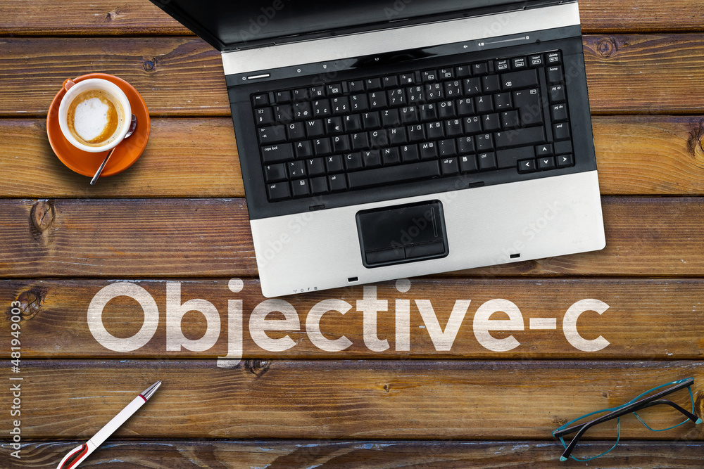 Poster objective-c programming language. word objective-c on wooden desk and laptop