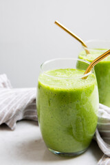 Green Smoothie served in a glass with a straw on a marble table top
