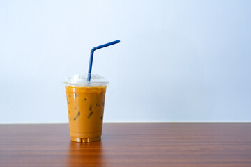 Cup iced coffee with milk on wooden table against blue wall.