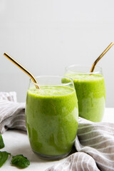 Green Smoothie served in a glass with a straw on a marble table top