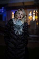 Portrait of a beautiful young girl on the street of a night city with insufficient lighting.