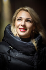 Portrait of a beautiful young girl on the street of a night city with insufficient lighting.