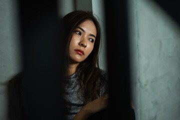 Young woman sitting sad with shadow foreground, depression emotion, looking space in dark room,...