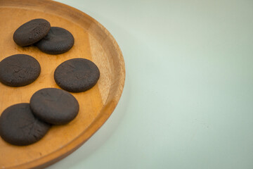Close up of chocolate cookies over the wooden plate, with negative space.  That image perfect for food pamphlet, product poster, product promotion and ads.