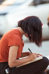 Beautiful girl drawing a sketch in the city