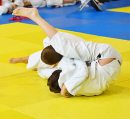 Two Boys judoka in kimono compete on the tatami 