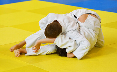 Two Boys judoka in kimono compete on the tatami 