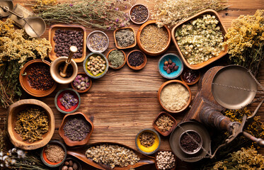 Natural medicine background. Assorted dry herbs in bowls and brass mortar on rustic wooden table.