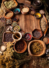 Natural medicine background. Assorted dry herbs in bowls and brass mortar on rustic wooden table.