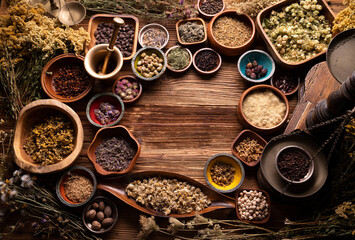 Natural medicine background. Assorted dry herbs in bowls and brass mortar on rustic wooden table.