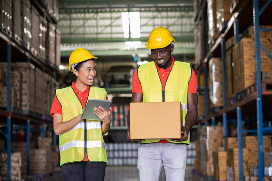 Africa American engineer woman holding tablet wearing safety helmet and vest standing in the automotive part warehouse. Looking at friend. Portrait of worker. Logistic and business concept