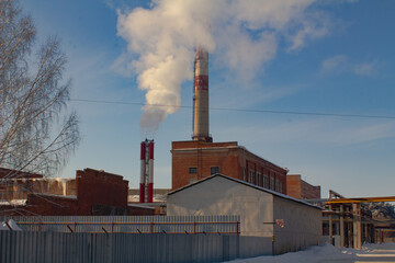 Industrial pipe, with white steam (smoke) from it. Against the background of factories, workshops.