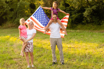 Fototapeta premium happy family with the flag of america USA at sunset outdoors