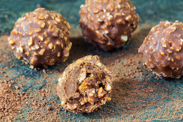 Group of chocolate sweet candy, bonbons on stone texture with cocoa powder