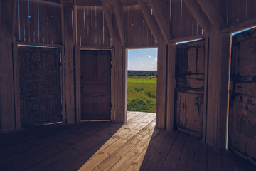 Inside white wooden Rotunda building with many doors with a view to a green meadow grass field
