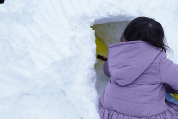 雪でかまくら作りを楽しんでいる女の子