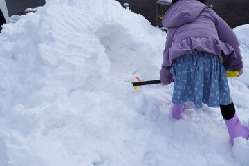 積もった雪でかまくら作りをしようと頑張っている女の子