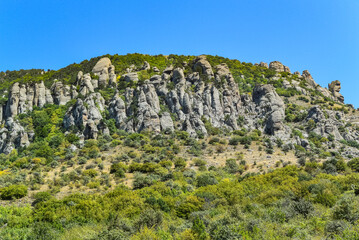 Ancient limestone high mountains of rounded shape in the air haze. The Valley of Ghosts. Demerji. May 2021. Crimea. Russia.