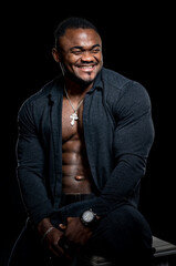 Naklejka na ściany i meble Full length view of the african american bodybuilder standing confidently on black studio background. Man demonstrating his press and muscles