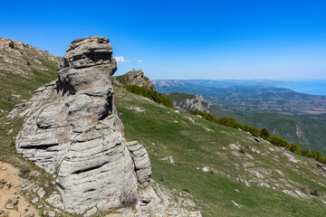 Ancient limestone high mountains of rounded shape in the air haze. The Valley of Ghosts. Demerji. May 2021. Crimea. Russia.