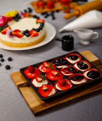 Obraz na płótnie Canvas Sweet cheesecake mini decorated with fresh berry fruits, and flowers on a wooden plate , for birthday, Valentine day and celebration