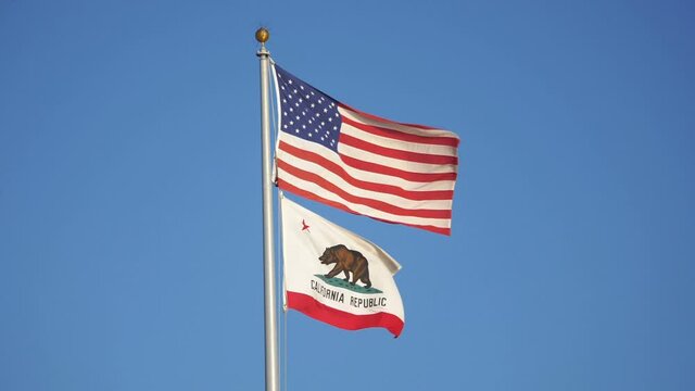 United States flag and california state flag waving in the wind in slow motion 180fps