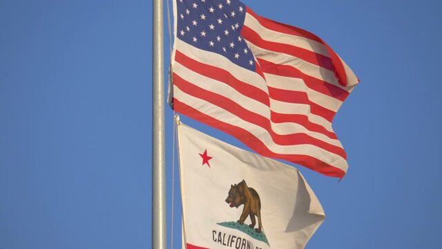 United States flag and california state flag waving in the wind in slow motion 180fps