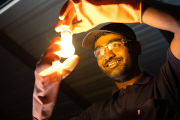 happy electrician after fixing ceiling light with safety workware - Concept of home repair and...