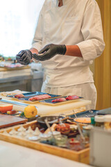 Chef is making sushi at a bar in a Japanese restaurant.
