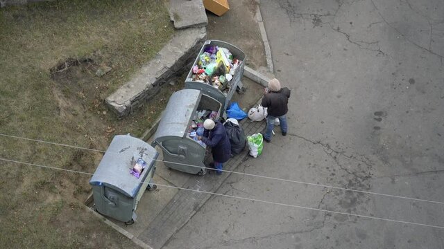 Belaya Tserkov, Ukraine, November 22, 2021: Beggars man and woman looking for food in the trash can