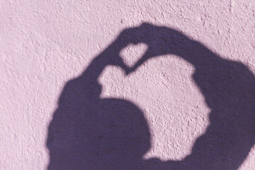 The shadow of a woman on the wall, which shows a heart with her hands. Symbol of love
