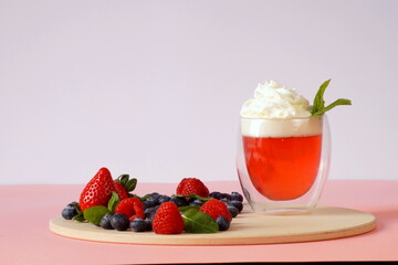 Pink dessert - jelly with whipped cream for breakfast decorated with fresh strawberries, raspberries and blueberries