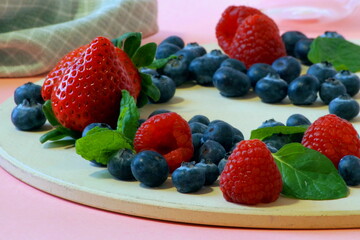 Fresh berries - strawberries raspberries and blueberries and fragrant mint leaves photographed close up