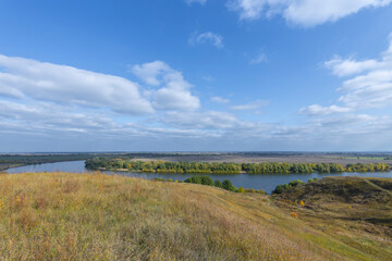 Autumn landscape with a view of the river and endless expanses of fields. Panoramic landscape with river and field and trees.