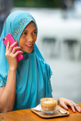 Happy muslim businesswoman in hijab at office break. Smiling Arabic woman talking on smartphone.