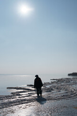 A woman silhouette enjoying winter while walking on a frozen lake with blue sky in the background. Freedom