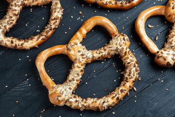 Fresh prepared homemade soft pretzels. Different types of baked bagels with seeds on a black background