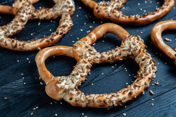 Fresh prepared homemade soft pretzels. Different types of baked bagels with seeds on a black background.