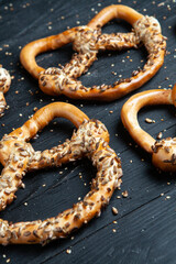 Fresh prepared homemade soft pretzels. Different types of baked bagels with seeds on a black background.