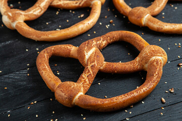 Fresh prepared homemade soft pretzels. Different types of baked bagels with seeds on a black background.