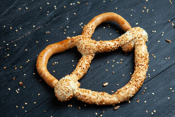 Fresh prepared homemade soft pretzels. Different types of baked bagels with seeds on a black background.