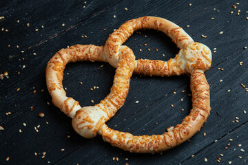 Fresh prepared homemade soft pretzels. Different types of baked bagels with seeds on a black background.