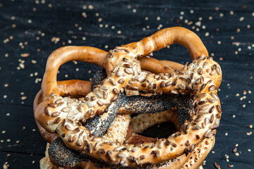 Fresh prepared homemade soft pretzels. Different types of baked bagels with seeds on a black background.