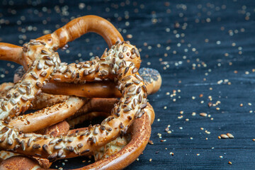 Fresh prepared homemade soft pretzels. Different types of baked bagels with seeds on a black background.