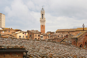 The Tower of Magia stands out above the tile rooftops of Siena Italy. © Jack