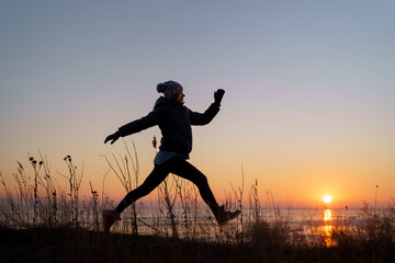Woman silhouette jumping in natural beautiful sunset. Motivation
