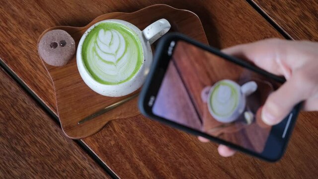 Food blogger filming on phone hot matcha latte for new content in social media online, digital lifestyle. Vertical shot