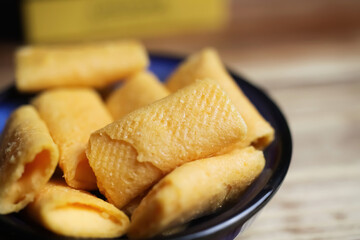 Closeup of isolated french small mini  baked cheese crepe rolls (petite crepes fourrees) with cheese filling on wood table