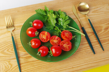 Sliced and whole cherry tomatoes with parsley on a green plate.